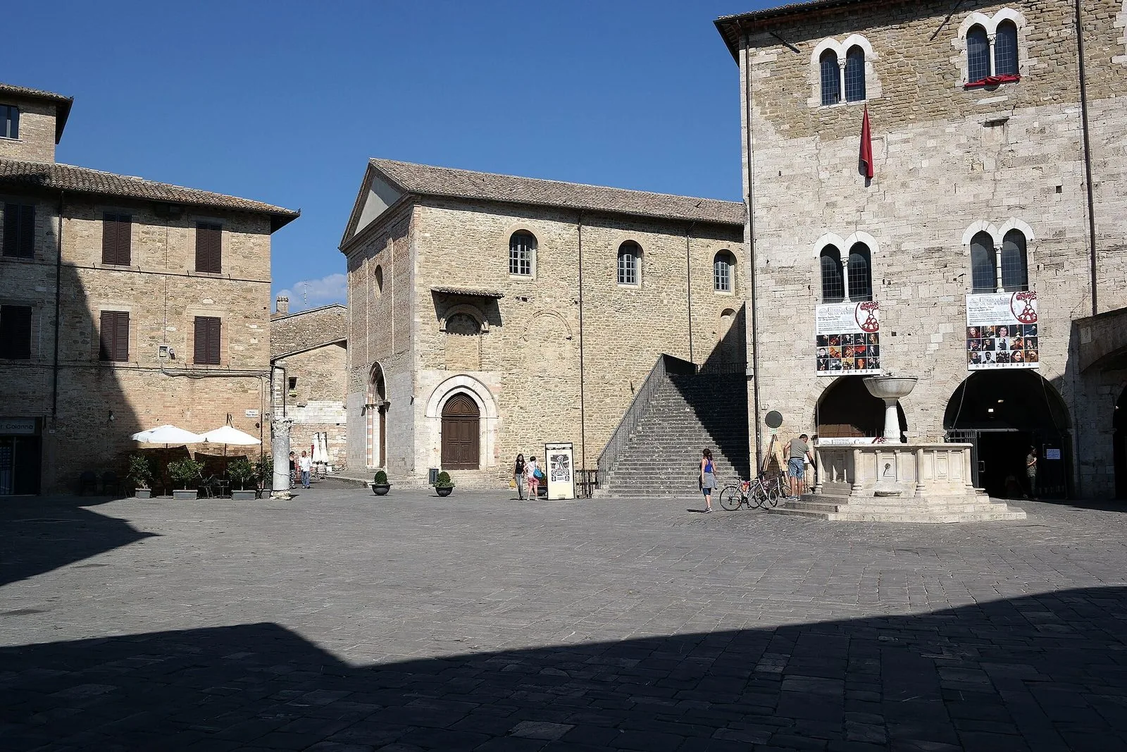 Piazza Silvestri a Bevagna con la fontana, il Palazzo dei Consoli e una chiesa romanica in pietra